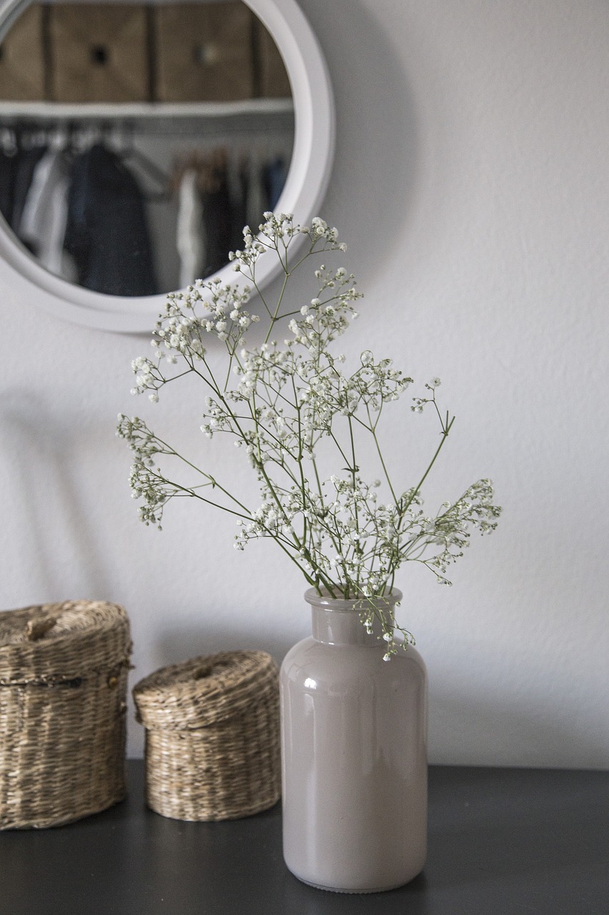 Vase with gypsophila flowers and mirror in the background