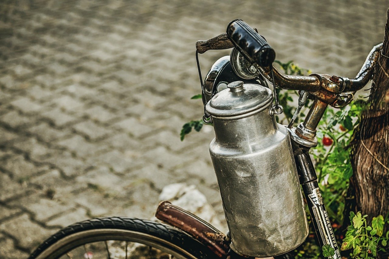 Milk Can of the yesteryears hung on the handle of a bicycle