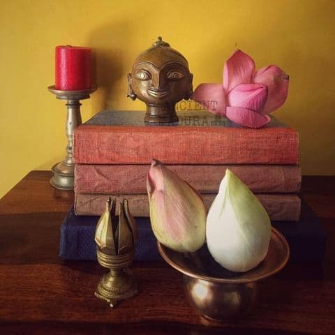 decor setup showing a Gauri head, and brass artefacts surrounding it with lotus flowers.