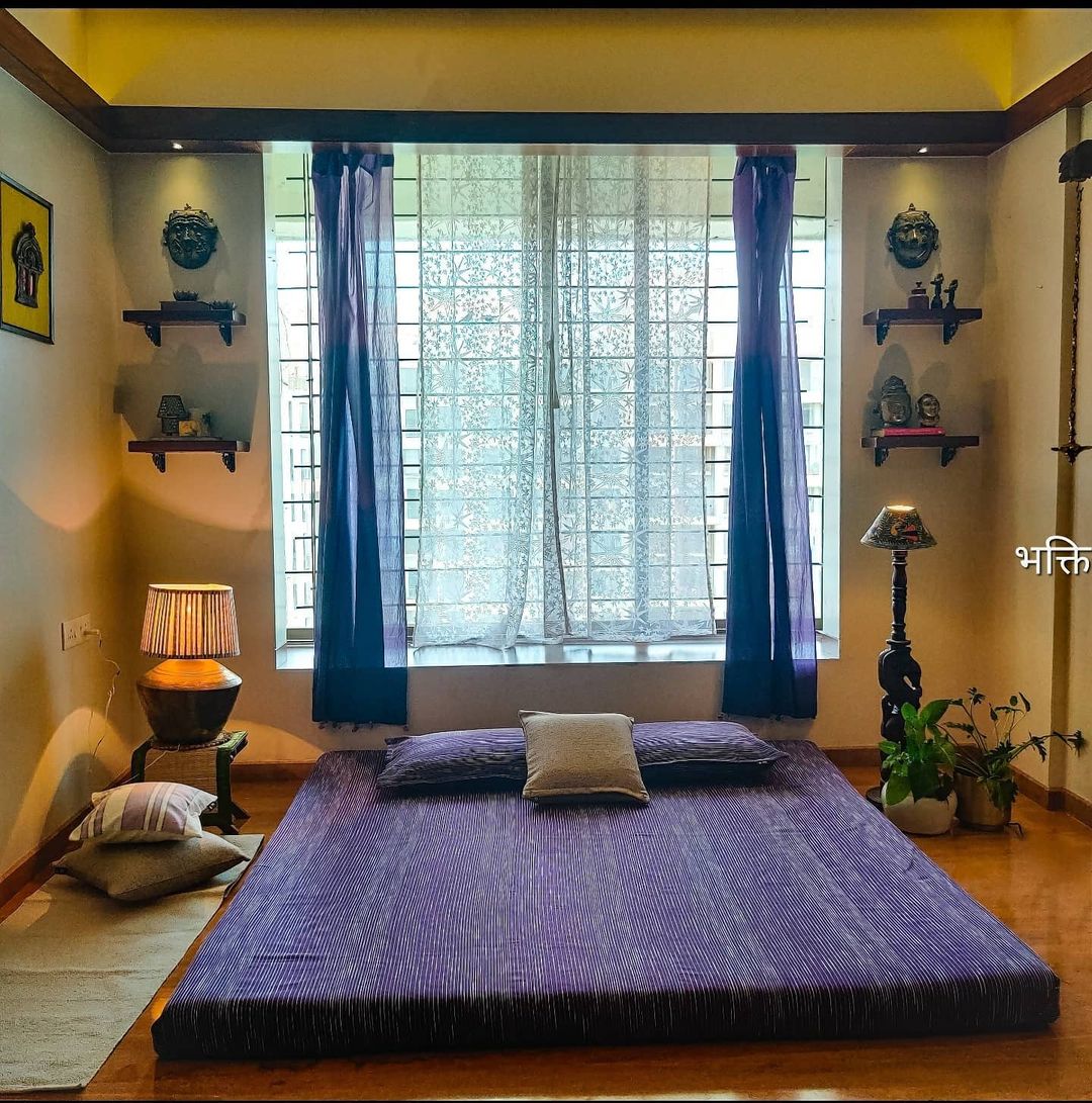 bedroom layout with symmetrical arrangements of barss and bronze pieces along wither side of the windows on shelves