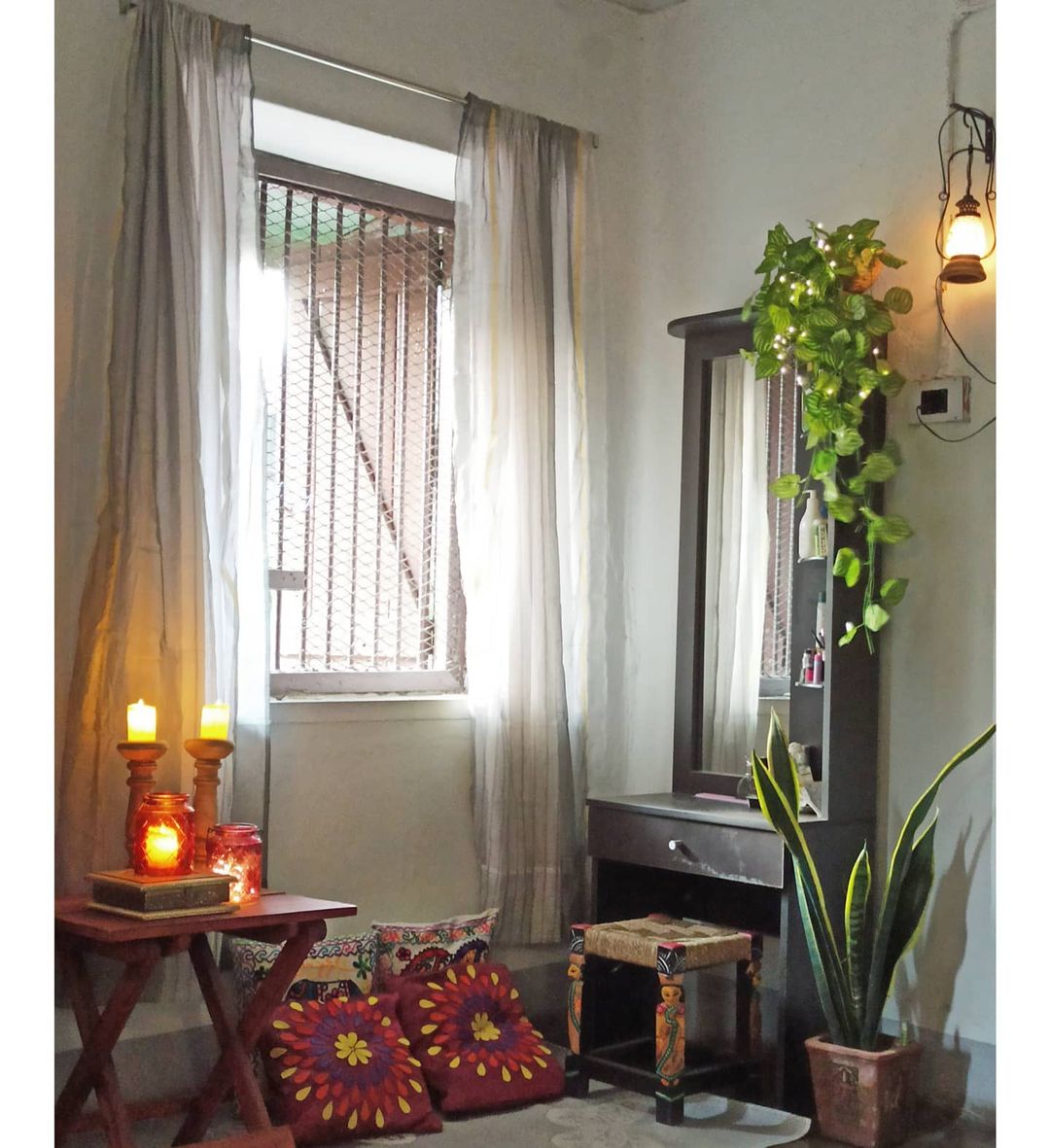 A corner of Shaoni's room decor with a meshed wondow, wooden candlestands and a hanging lantern