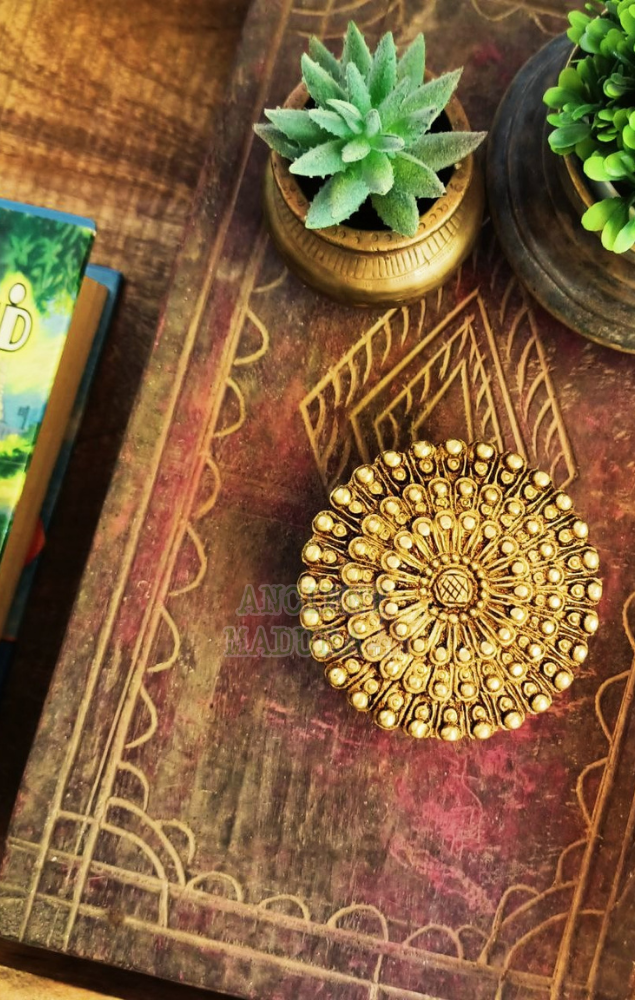 A brass kumkum holder in a flatlay arrangement