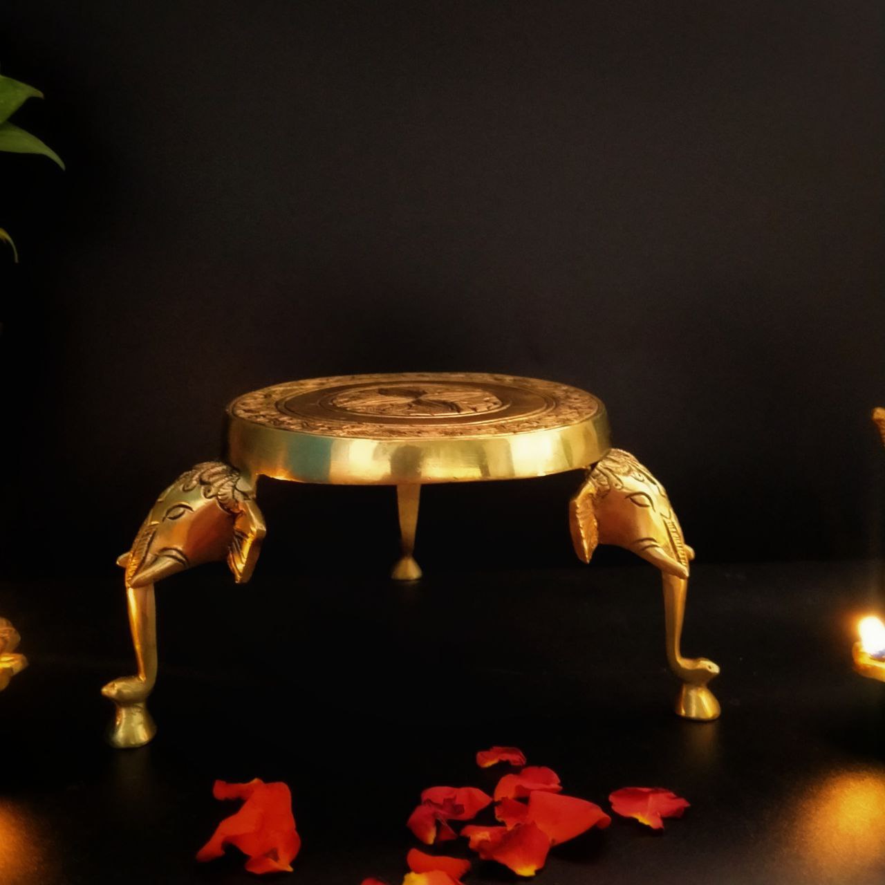 A brass poja stand with an elephant head design on the legs