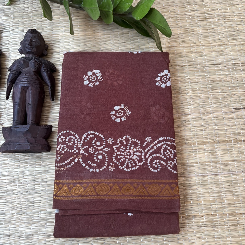 Brown sungudi batik saree with white floral rosette motifs, gold zari border and framed floral pallu with wave accents