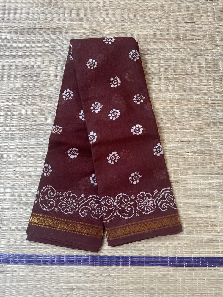 Brown sungudi batik saree with white floral rosette motifs, gold zari border and framed floral pallu with wave accents