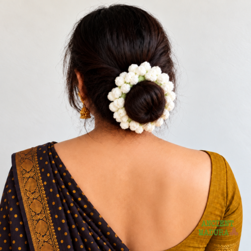 Artificial jasmine hair scrunchie crocheted from white woollen yarn, worn around a bun with a saree