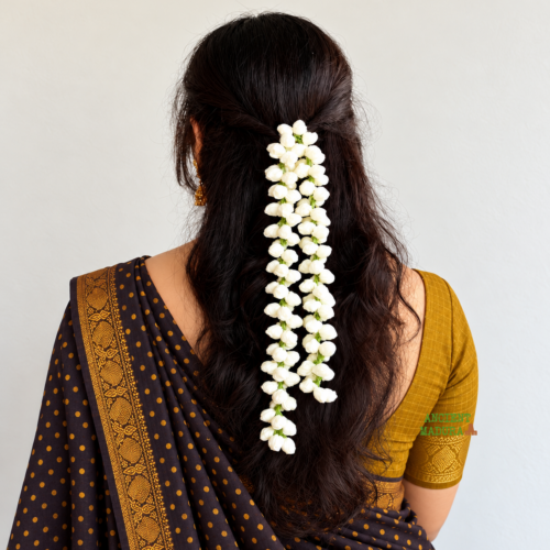Artificial jasmine flower gajra crocheted from white woollen yarn, worn in a half-up hairstyle with a saree